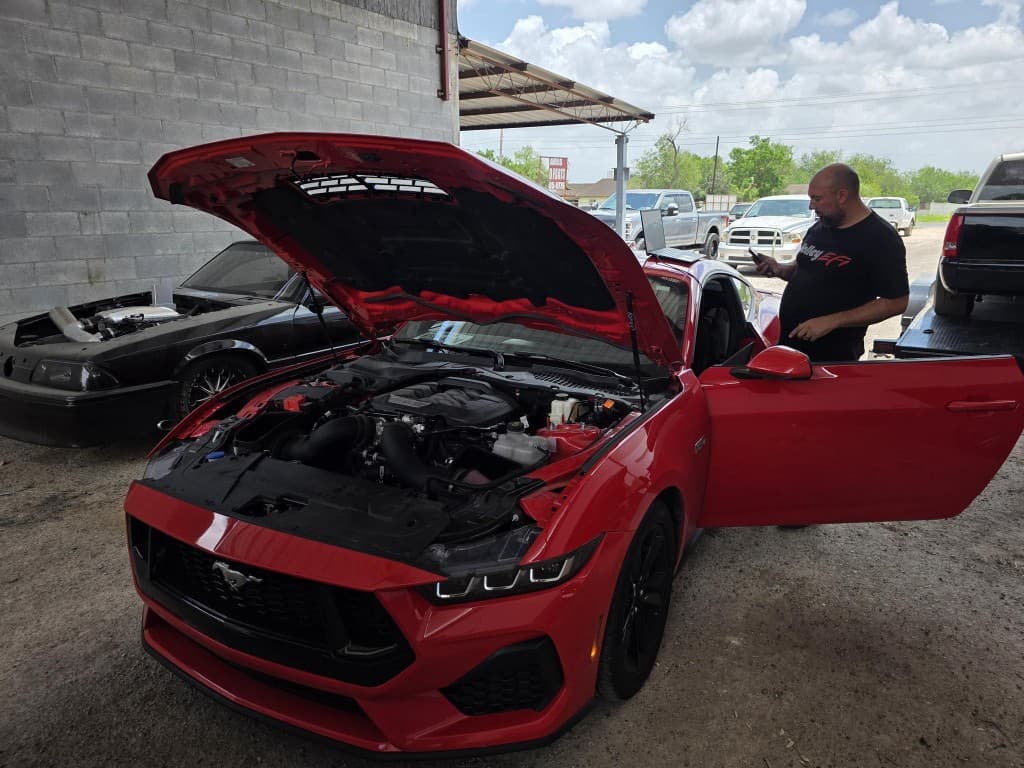 Red 2024 Mustang GT with hood up at the shop