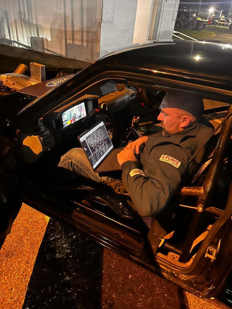 Tuner inside a race car at night with a laptop